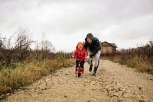 Dzieci z uśmiechem pomagające w myciu świeżych owoców do przetworów, ucząc się przez zabawę.