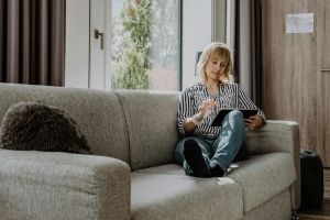 Kobieta korzystająca z tabletu w inteligentnej kuchni, symbolizująca komfort życia z nowoczesnymi technologiami w domu pasywnym.