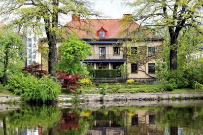 Nowoczesny dom pasywny z pięknie zagospodarowanym ogrodem, otoczony zielenią i idealnie przyciętym trawnikiem.