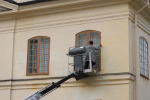 Dron inspekcyjny skanujący elewację nowoczesnego domu pasywnego z panelami słonecznymi.