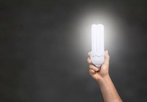 Dłoń trzymająca nowoczesną żarówkę LED, symbolizującą energooszczędność i ekologię w oświetleniu ogrodowym.
