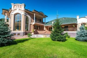 Nowoczesny dom pasywny z dużymi oknami i tarasem otoczonym bujną zielenią, symbolizujący spokój i harmonię z naturą.