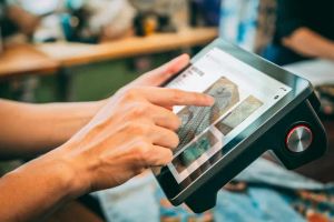Tablet z interfejsem inteligentnego domu, sterujący oświetleniem i klimatyzacją w salonie, w rękach użytkownika