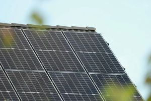 Panele fotowoltaiczne na dachu domu, generujące zieloną energię do ładowania EV.