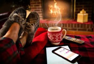 Kobieta relaksująca się na kanapie z psem, sterująca inteligentnym domem za pomocą tabletu