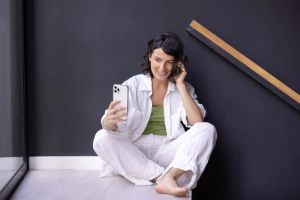 Kobieta sterująca inteligentnym domem za pomocą smartfona w nowoczesnym salonie