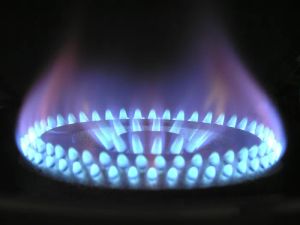 Kobieta w nowoczesnej kuchni używająca inteligentnych urządzeń, symbolizująca efektywność energetyczną i zarządzanie odpadami.