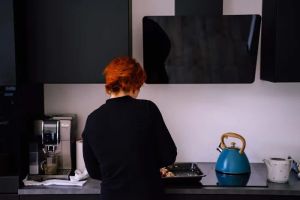 Kobieta korzystająca z inteligentnych urządzeń w nowoczesnej kuchni, symbolizująca dostępność i niezależność.